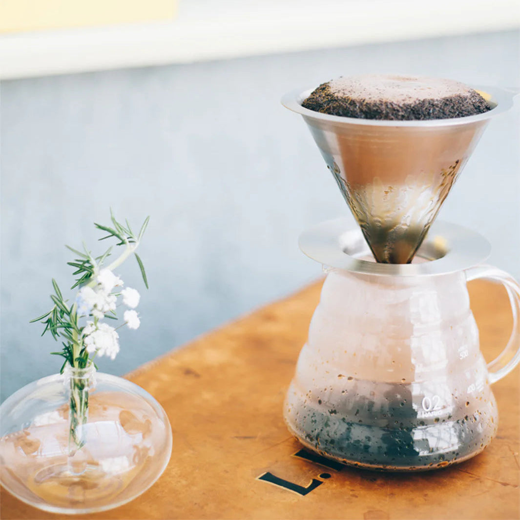 Coffee brewing process with a glass carafe and filter on a wooden surface.
