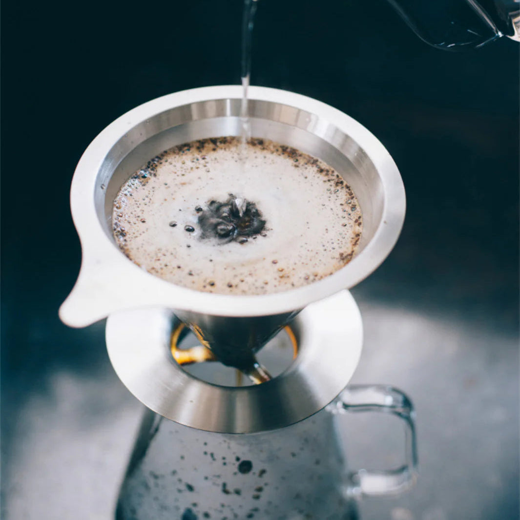 Coffee being poured into a filter basket on a dark background