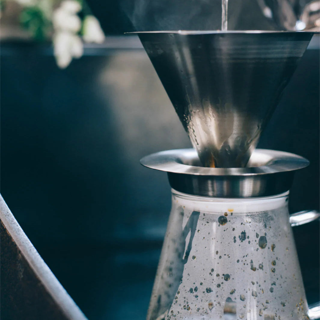 Pouring liquid into a metal funnel with a blurred background
