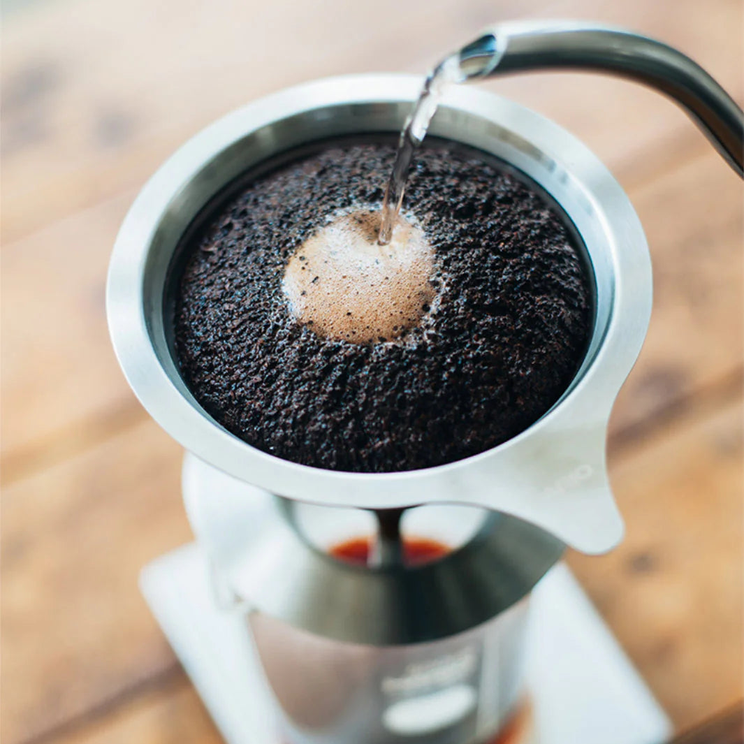 Coffee being brewed into a filter with a wooden surface in the background