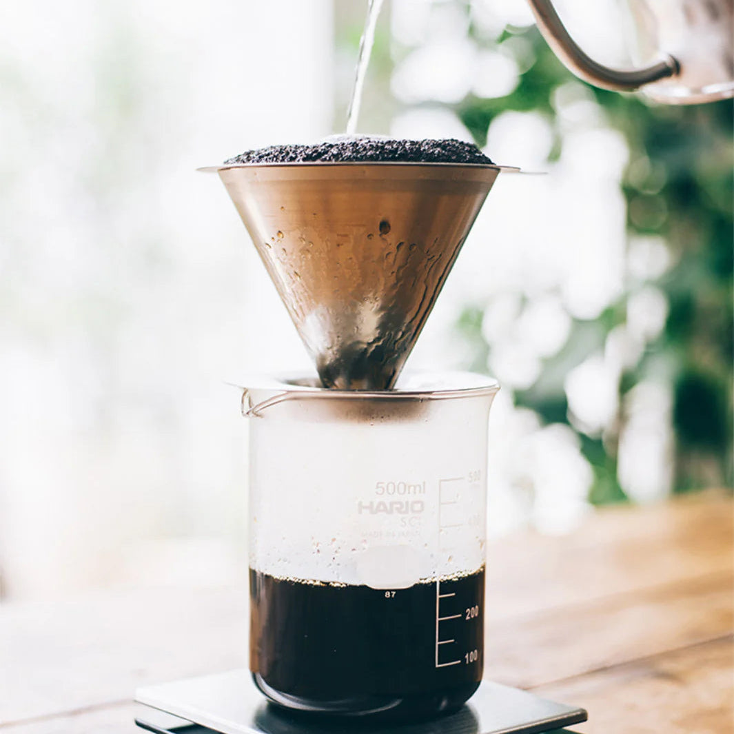 Coffee brewing process with a pour-over setup on a wooden surface.