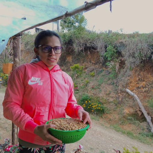Person holding a bowl of food outdoors with a natural background