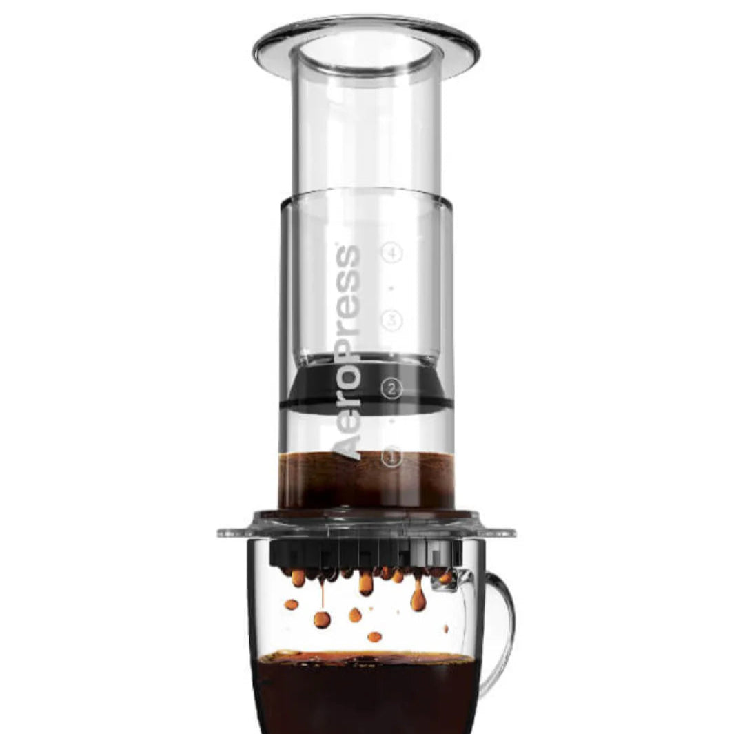 AeroPress coffee maker with coffee being brewed on a white background