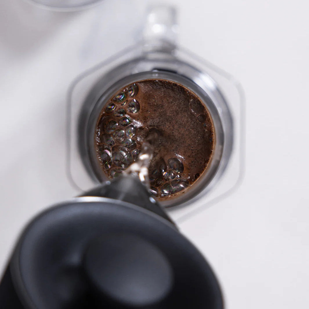 Close-up of a coffee filter with ground coffee being pressed into it.