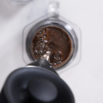 Close-up of a coffee filter with ground coffee being pressed into it.